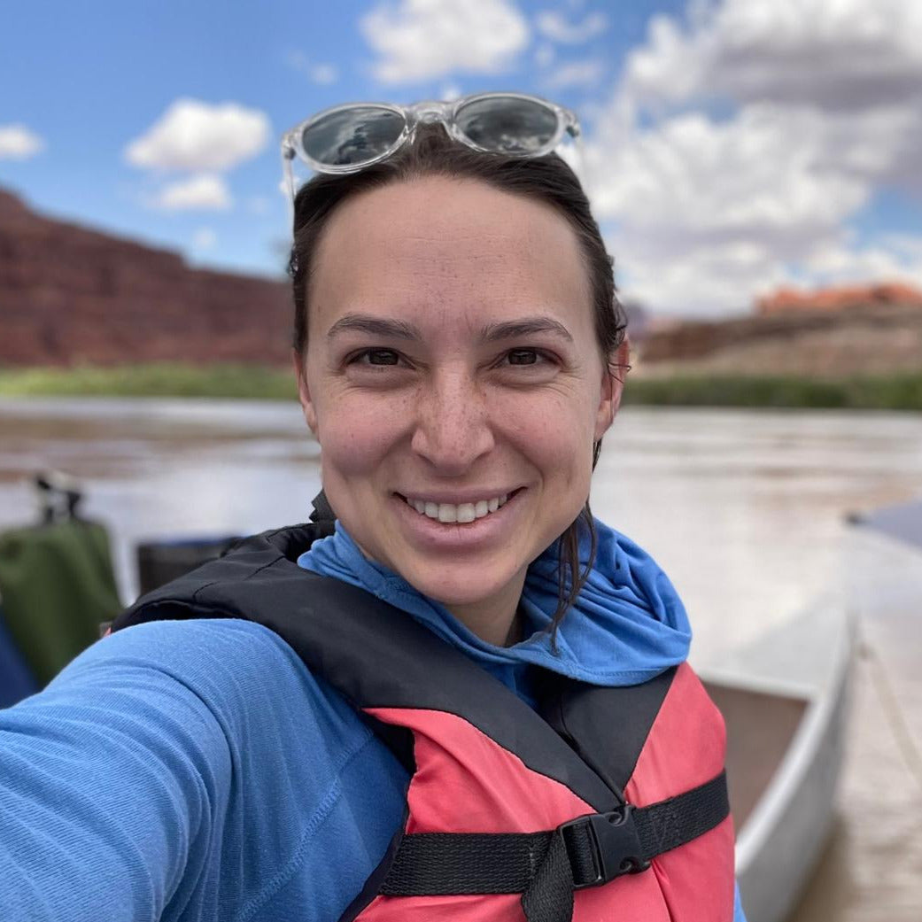 Person wearing a life jacket with a scenic background of water and mountains.